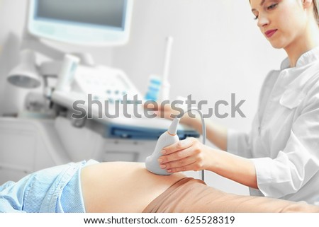 Pregnant woman undergoing ultrasound scan in modern clinic Royalty-Free Stock Photo #625528319