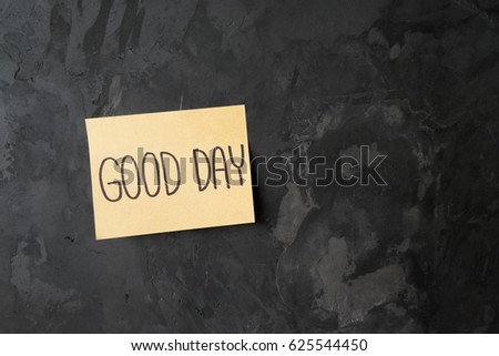 handwriting of message "GOOD DAY" on a sticky note paper on abstract concrete wall