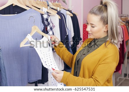 Clothing store owner checking everything its okay. Blonde woman sorting clothes.