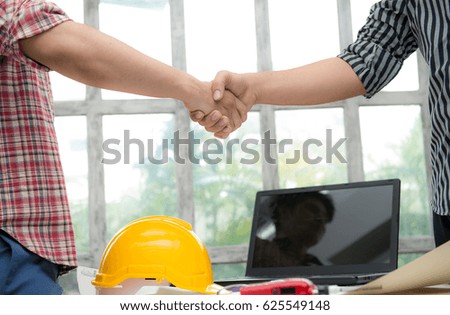 Contractor and company executive sealing a deal shaking hands.Concept of new job opportunities and city development,Close-up of business people handshaking over helmets,Documents,Worker tool,Engineer