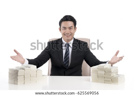 A happy young businessman show body language to invite with the open hand wide, among the huge amount of money on desk, on white background, concept of business, financial and investment.