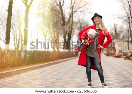 Mother keeps the daughter on hands on walk in the park
