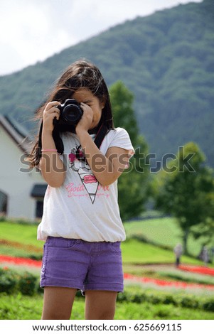 A girl who takes a photograph in summer highland.

