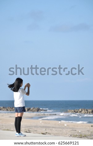A girl who takes a photograph. Background,beach,blue,sky.
