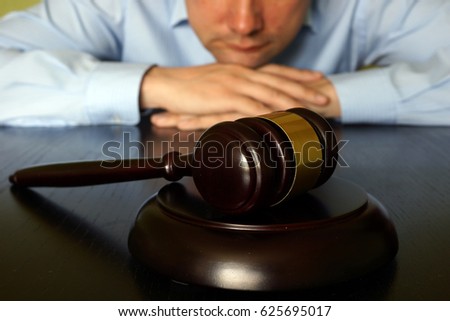 Justice concept. Man is sitting at the table opposite gavel. Royalty-Free Stock Photo #625695017