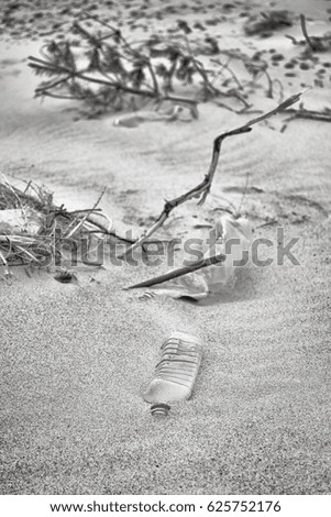 Black and white picture of plastic bottles left on a beach, selective focus, environmental pollution concept picture.