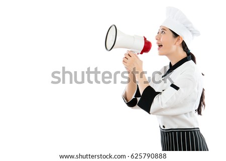 asian beautiful chef standing on the white wall background talking to the blank copyspace using loudspeakers megaphone showing restaurant advertising text.
