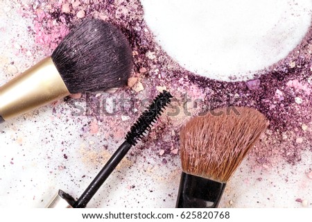 Makeup brushes and mascara applicator on white marble background, with traces of powder and blush forming frame. Horizontal template for makeup artist's business card or flyer design, with copy space