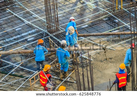 Construction workers are pouring concrete in post-tension flooring work. Mason workers carrying hose from concrete pump or also known as elephant hose during concreting work at construction site Royalty-Free Stock Photo #625848776