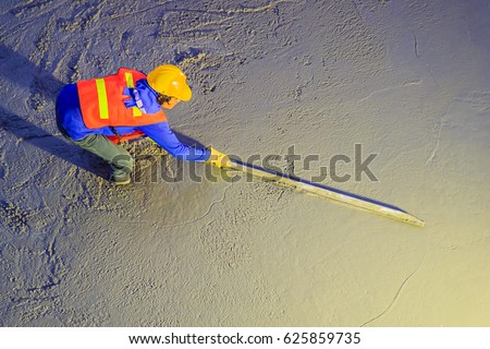 Mason worker leveling concrete with trowels, mason hands spreading poured concrete. Concreting workers are leveling poured liquid concrete on a steel reinforcement to form strong floor slab. Royalty-Free Stock Photo #625859735