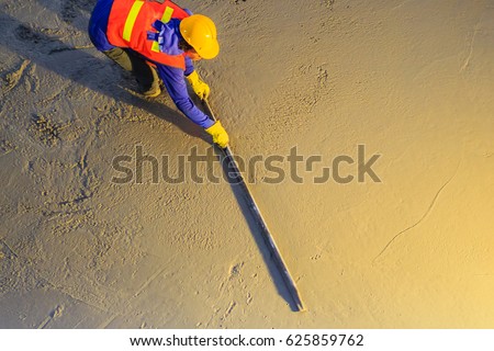 Mason worker leveling concrete with trowels, mason hands spreading poured concrete. Concreting workers are leveling poured liquid concrete on a steel reinforcement to form strong floor slab. Royalty-Free Stock Photo #625859762