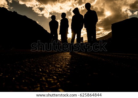 Four people stand on the road during the sunset time.