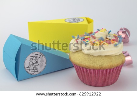 Happy Birthday cup cake with star sprinkles isolated on white background with paper party cake holders in background