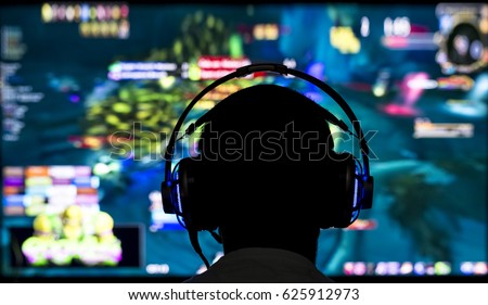Young gamer playing video game wearing headphone.