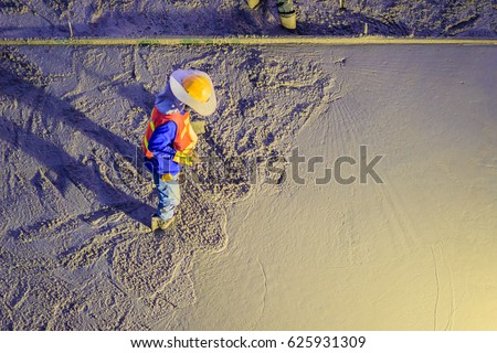 Mason worker leveling concrete with trowels, mason hands spreading poured concrete. Concreting workers are leveling poured liquid concrete on a steel reinforcement to form strong floor slab. Royalty-Free Stock Photo #625931309