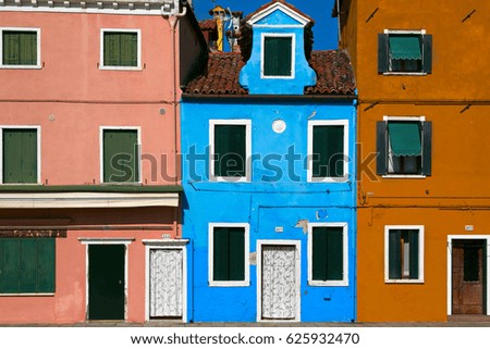 Bright colorful houses in Burano village, Italy. Facades of venetian houses in blue, pink and beige. Venice landmark Burano island.