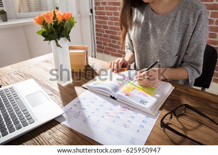 Close-up Of A Businesswoman Making Agenda On Personal Organizer At Workplace Royalty-Free Stock Photo #625950947