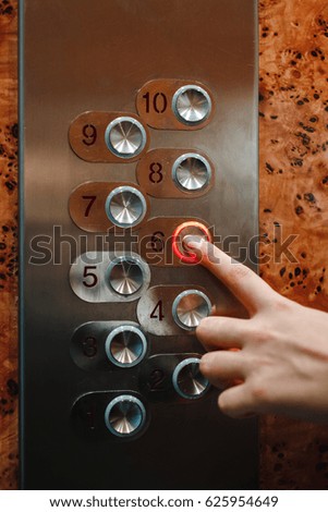 Buttons on the elevator under a burnished brown background.
