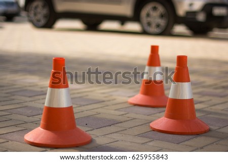 Side view of Two orange road cones on a sidewalk tile. Block the traffic. Road bollard Traffic cones in the car park