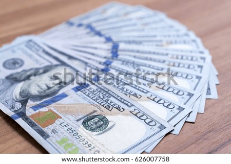 One hundred dollar banknotes stacked on wooden background