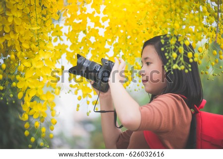 Beautiful Asian girl take photo with blooming yellow flower,Thailand travel concept
