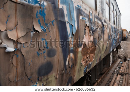 Old trains are parked outdoors where they are exposed to the heat of sunlight and rain, resulting in cracking and rusting.