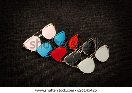 Five sunglasses of different colors on a black background