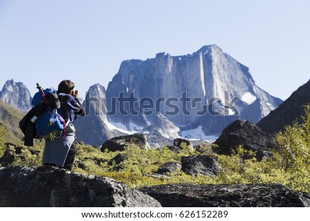 A person taking a picture of a huge mountain during a trekking