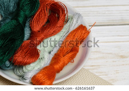 Threads for hand embroidery on wooden background.