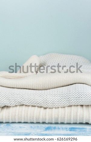 Knitted wool sweaters. Pile of knitted winter clothes on wooden background, sweaters, knitwear, space for text