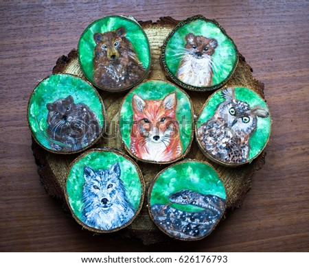 Collection of painted forest animals on a cut pieces of wood. Background of brown wooden cut tree trunk. Red fox, grey wolf, snake, owl, bear, weasel and beaver. Wild nature