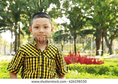 Cute asian young boy on park background with room for text