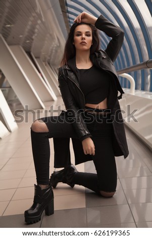 fashionable young teenager girl walking on the street wearing rock clothes - leather jacket, fishnet black pantyhose under the torn jeans
