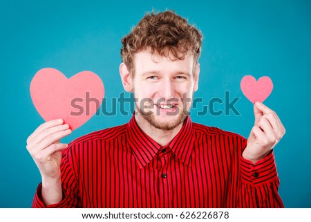 Romance affection feelings concept. Cheering man holding hearts. Adult man in red shirt showing love symbols.