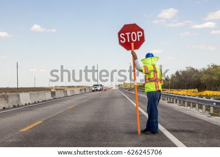 Road construction on the highway, Worker holds a stop sign to control the traffic