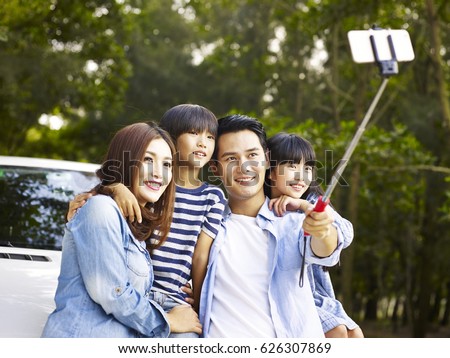 asian family with two children taking a selfie during a trip.