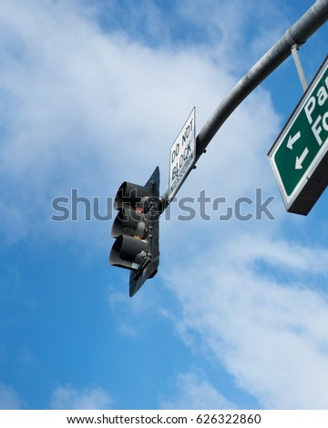 A pole with a traffic light and signs on it against a blue sky background.