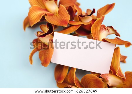 Business card mock up with orchid flowers on turquoise background.