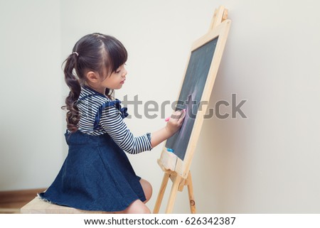 Asian girl draw a flower to blackboard with chalk in vintage background, in class room, kid, child, student, and school concep
