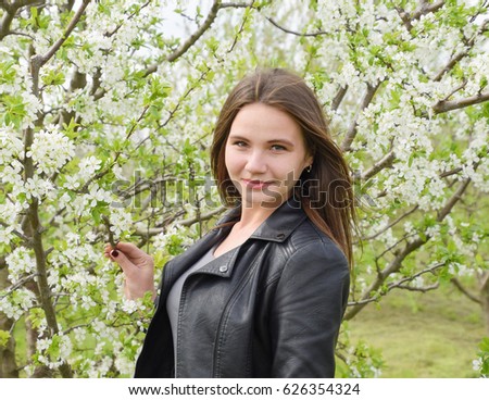 Beautiful fairy young girl in a flowering plum garden. Portrait of a girl on a white flowers background.