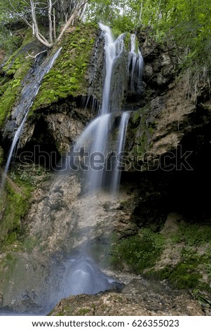 Waterfall on a mountain stream with rocks covered with moss