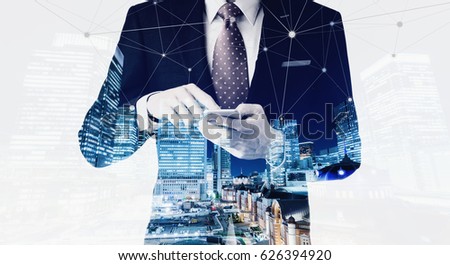 Business concept for information, communication, connection technology - double exposure effect of office man and panoramic modern city skyline bird eye aerial night view under dramatic dark blue sky