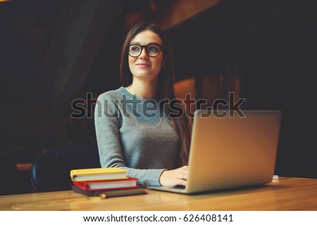Dreamy attractive female student thinking about coursework strategy sitting in university library with laptop computer connected to wireless internet,talented editor of online issue creating article 
