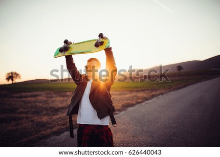 Skater man holding his skateboard above his head on the street