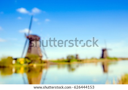 The charming landscape with windmills in Kinderdijk, Netherlands, Europe against a background of cloudy sky reflection in the water. Blur effect.