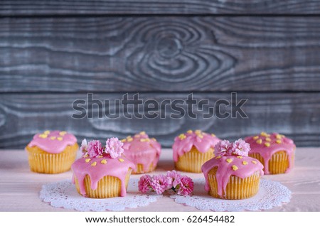 Cupcakes with pink frosting on the table. The holidays and events. Beautiful floral decor. Cooking desserts. Grey background for text. Selective focus.