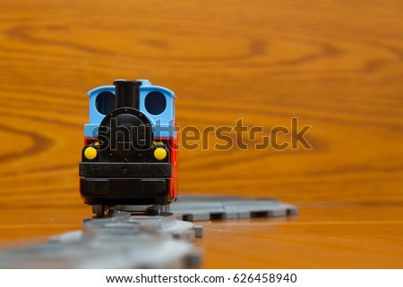 The toy train goes on rails. On a brown background