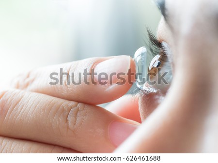 Young woman putting contact lens in her right eye, close up Royalty-Free Stock Photo #626461688