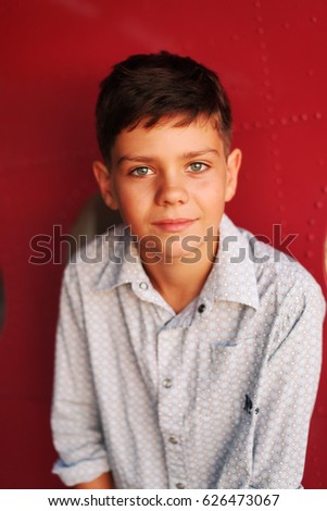 Kid, boy on an old little plane, summer, sunset, red background