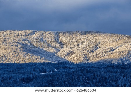 Snow covered beautiful mountain peaks and soft white clouds on blue sky background.